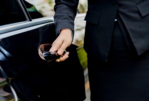 Professional chauffeur opening car door for client – black car service.